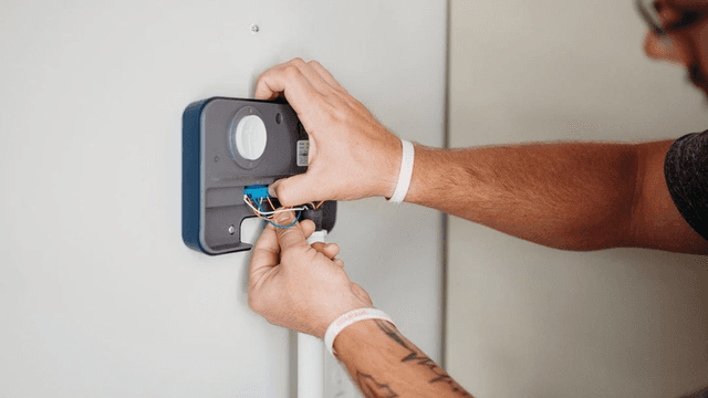 Rachio Smart Sprinkler Controller installed on a wall paired with app screen